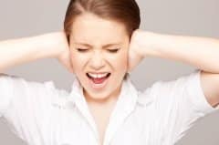 Stressed woman with her eyes closed, covering both ears with her hands