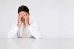 Man sitting at a desk with his face in his hands