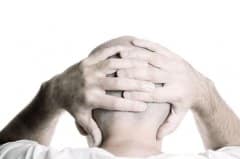 Person holds both hands to the head, desaturated black-and-white photo