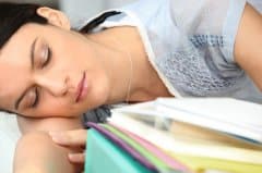 Woman asleep with her head resting on a stack of books