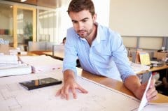 Man reviewing building plans at an office desk