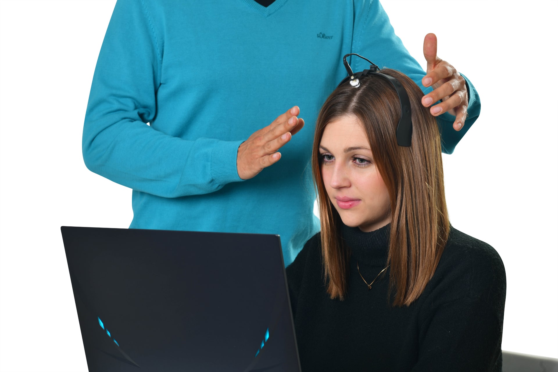 Practitioner fitting an electrode headset on a client at a laptop