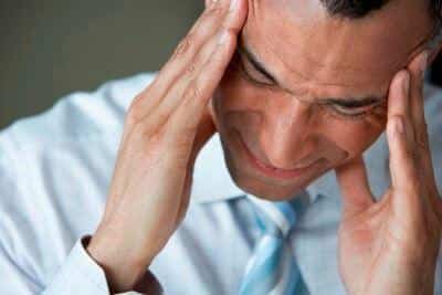 Mann hält sich mit beiden Händen die Schläfen, Ausdruck von Stress